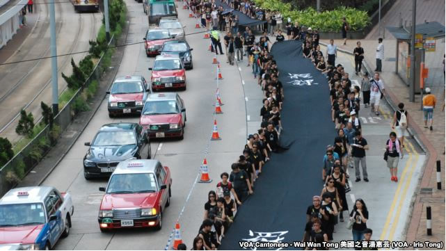 Những người phản đối cầm dải vải đen dài 500 mét tuần hành trên đường phố Hong Kong hôm Chủ nhật, để chứng tỏ họ quyết tâm muốn có phổ thông đầu phiếu thực sự, 14/9/2014